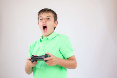 Little boy with green polo shirt concentrated with the game controller
