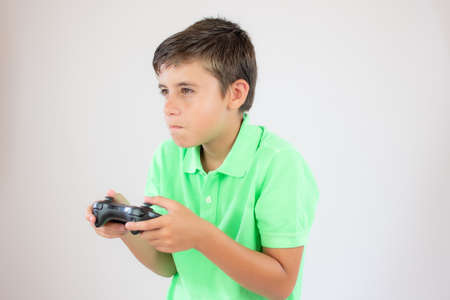 Little boy with green polo shirt concentrated with the game controllerの写真素材
