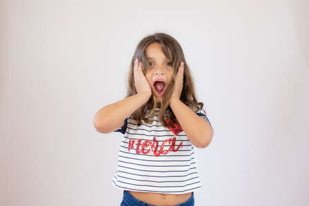 Beautiful little girl in striped shirt making surprise gesture