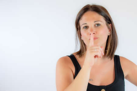 Beautiful young woman in black shirt making silence gestureの写真素材