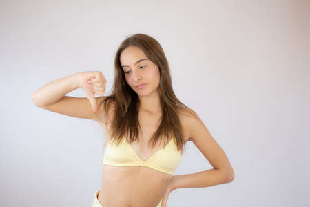 Pretty young girl in bikini making finger down gestureの写真素材