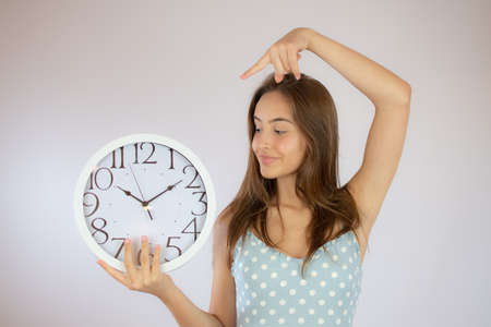 Pretty young girl in dress looking at a big clock