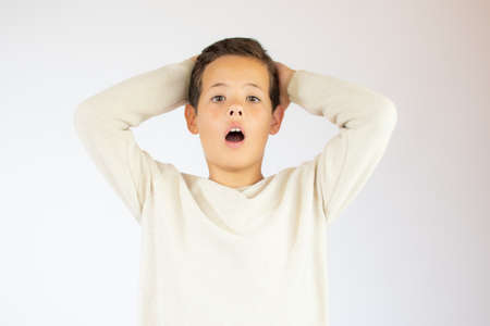 Handsome boy in beige sweater with surprised gesture