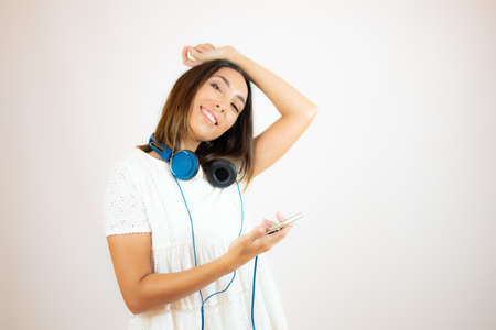 Beautiful woman in white dress with headphonesの写真素材
