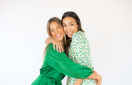 Two friends in green dresses pose together smilingの写真素材