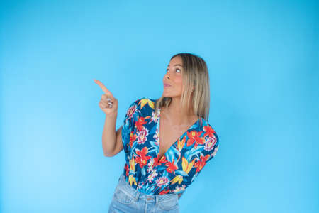 Pretty blond woman pointing on blue backgroundの写真素材