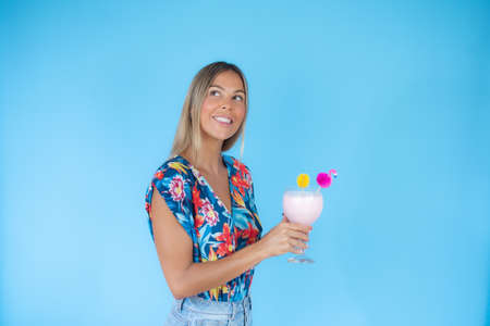 Blond woman with a drink on blue background smilingの写真素材