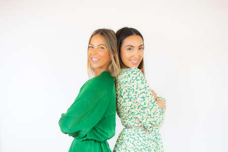 Two friends in green dresses pose together smilingの写真素材