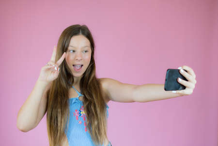 Smiling pretty girl taking a picture on pink background