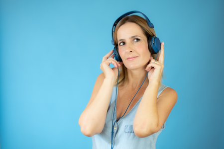 Woman in blue shirt with headphones on blue background