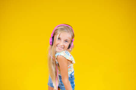 Smiling beautiful blonde girl with headphones on yellow backgroundの写真素材