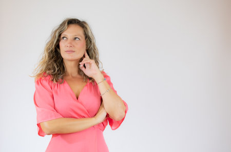 Pretty woman in pink dress with doubtful gestureの写真素材