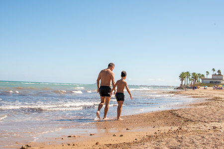 Father and little son sitting on the seasideの写真素材
