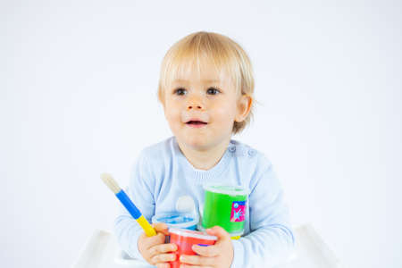 Amazed toddler boy with colorful paints on face isolated on white background