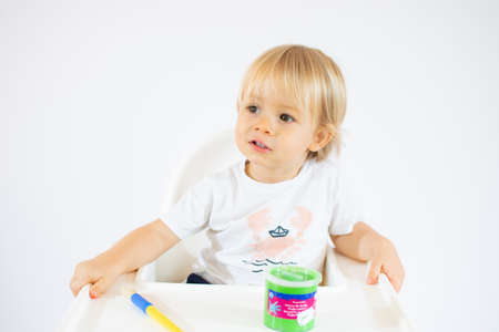 Amazed toddler boy with colorful paints on face isolated on white background