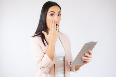 Portrait of a happy young business woman pointing fingers up at copy space isolated over white backgroundの写真素材