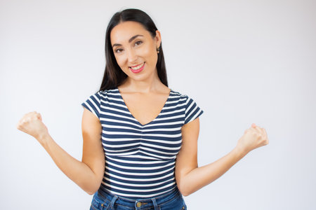 Successful woman raising arms in success gesture over white backgroundの写真素材