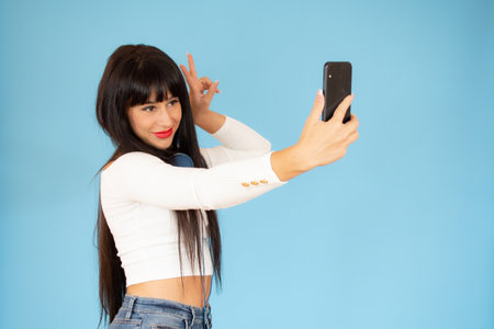 A beauty girl wearing headphones taking selfie over blue background.の写真素材