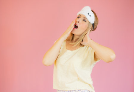 Young woman wearing pajama and sleep mask over pink isolated background