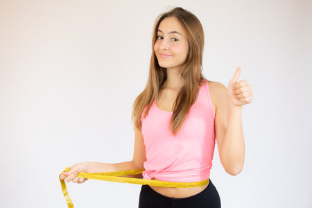 Portrait of a smiling young girl with long hair standing over white background, holding fingers crossed for good luckの写真素材