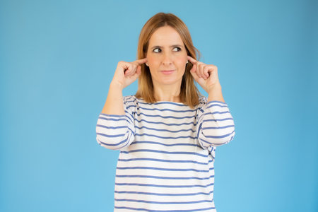 Young beautiful woman wearing casual t-shirt standing over blue isolated background covering one eye...