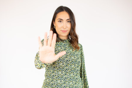 Young brunette woman wearing casual dress over white isolated background doing stop sing with palm of the hand. Warning expression with negative and serious gesture on the face.の写真素材