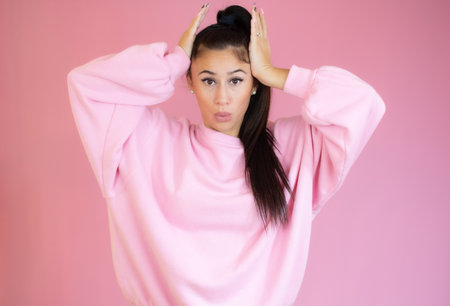 Surprised young woman in casual clothes over pink background. Looking at camera.の写真素材