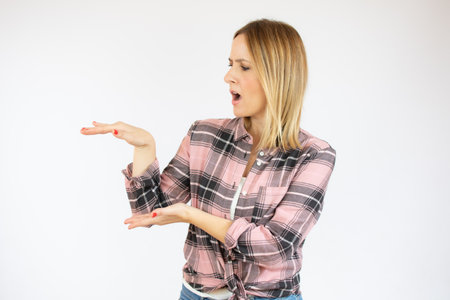 Young caucasian woman posing isolated holding something with both hands, product presentation.の写真素材