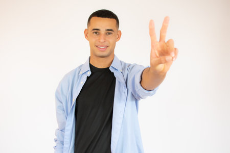 Young man with a gesture of victory over white background.の写真素材