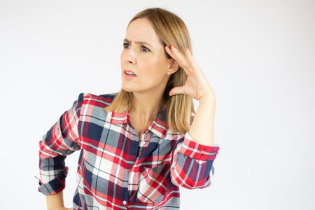 Young woman over isolated white background listening to something by putting hand on the ear