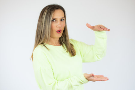 Young woman over isolated white background holding copy space imaginary on the palm to insert an adの写真素材