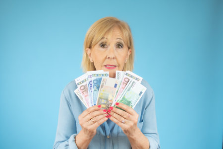 Savings, finances and people concept - smiling senior woman holding money banknotesの写真素材