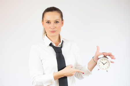 Business caucasian woman holding alarm clock on a white backgroundの写真素材