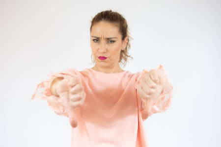 Young caucasian woman isolated on white background showing thumb down with two handsの写真素材