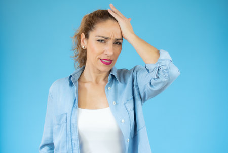 Beautiful woman wearing casual shirt over isolated background confuse and wonder about question. Uncertain with doubt, thinking with hand on head. Pensive concept.の写真素材