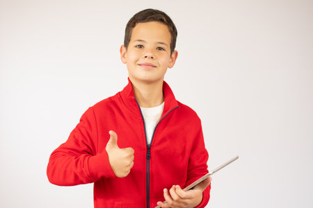 Portrait of a satisfied cute little kid playing games on tablet computer isolated over white backgroundの写真素材
