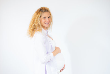 Young beautiful pregnant woman standing over white background.