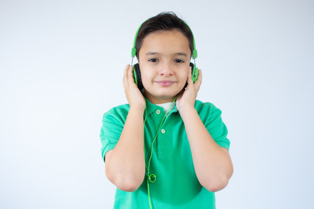 Attractive cute laughing happy boy listening to music and holding hands on headphones on a white backgroundの写真素材