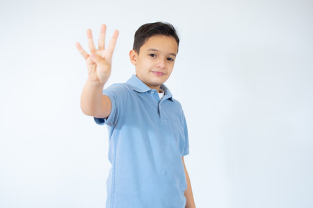 Beautiful kid boy wearing blue T-shirt standing over isolated white background showing and pointing up with fingers number four while smiling confident and happyの写真素材