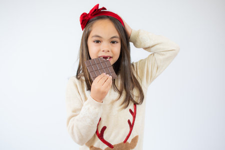 Beautiful little girl eating chocolate isolated over white background.の写真素材