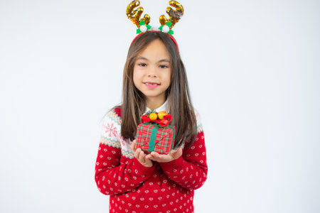 Joyful little girl in santa hat holding gift box in hands over white background.の写真素材
