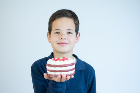Teenage boy showing a piece of cake on white backgroundの写真素材