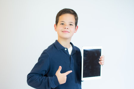 Portrait of a cute smiling boy using a tablet computer against a white background.