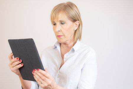 Portrait of senior woman using digital tablet over white background.の写真素材