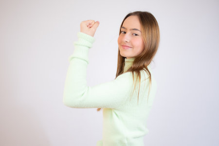Girl power concept - young teen girl showing her muscular arm for feminine and independent strength,studio shotの写真素材