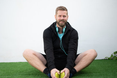 Relaxed smiling sportsman sitting outdoors and stretching.の写真素材