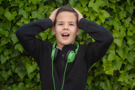 Young excited boy wearing headphones outdoors.の写真素材