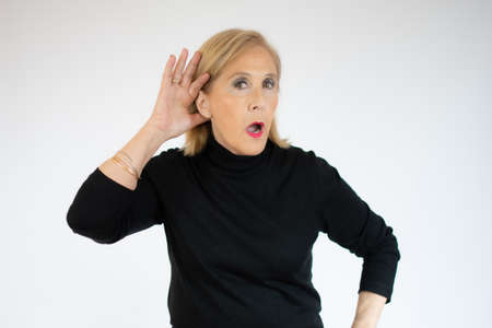 Senior woman with hand over ear listening and hearing to rumor or gossip. deafness concept.