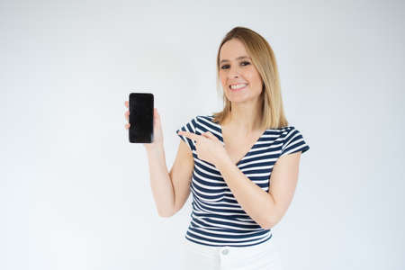 Young happy cheerful woman showing mobile phone over white background.
