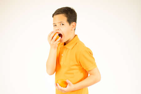 Young boy eating a orange isolated on white